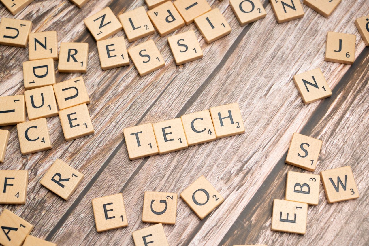 services-02 Wooden Scrabble tiles spelling 'TECH' on a textured surface, showcasing creativity.