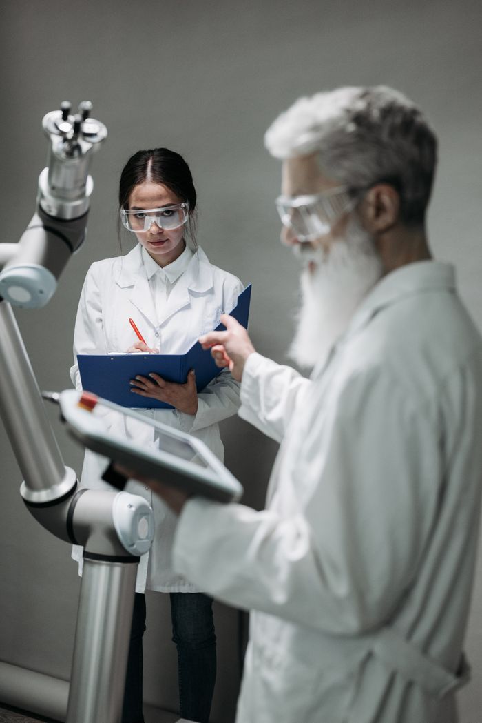 why-choose-us Researchers in lab coats interacting with advanced robotic arm technology.